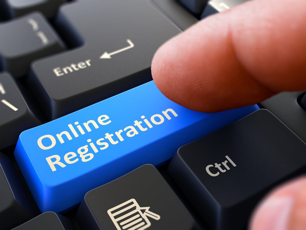 Online Registration - Written on Blue Keyboard Key. Male Hand Presses Button on Black PC Keyboard. Closeup View. Blurred Background.